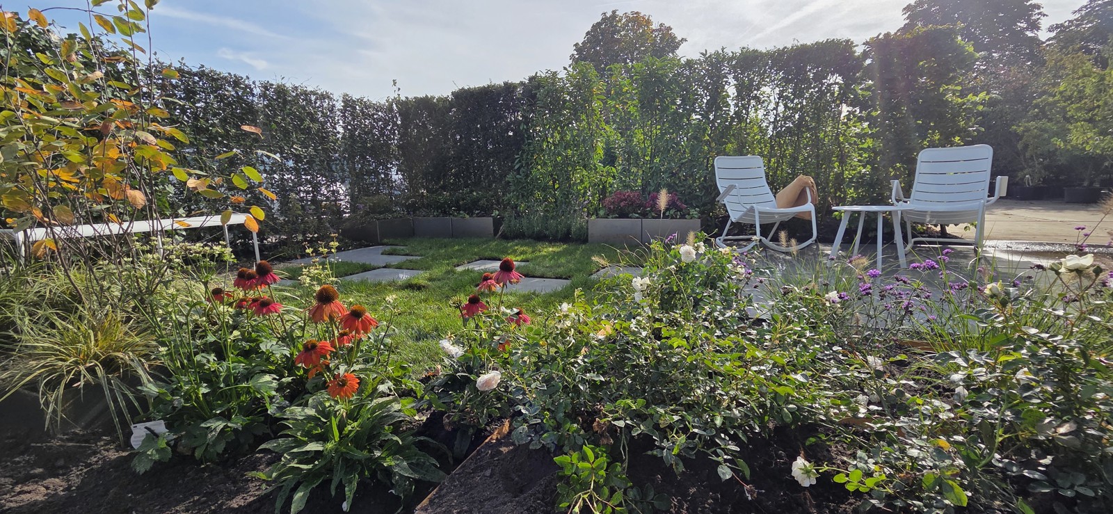 Overview of the Preverde show garden with flowering borders, grass, stepping stones and a seating area