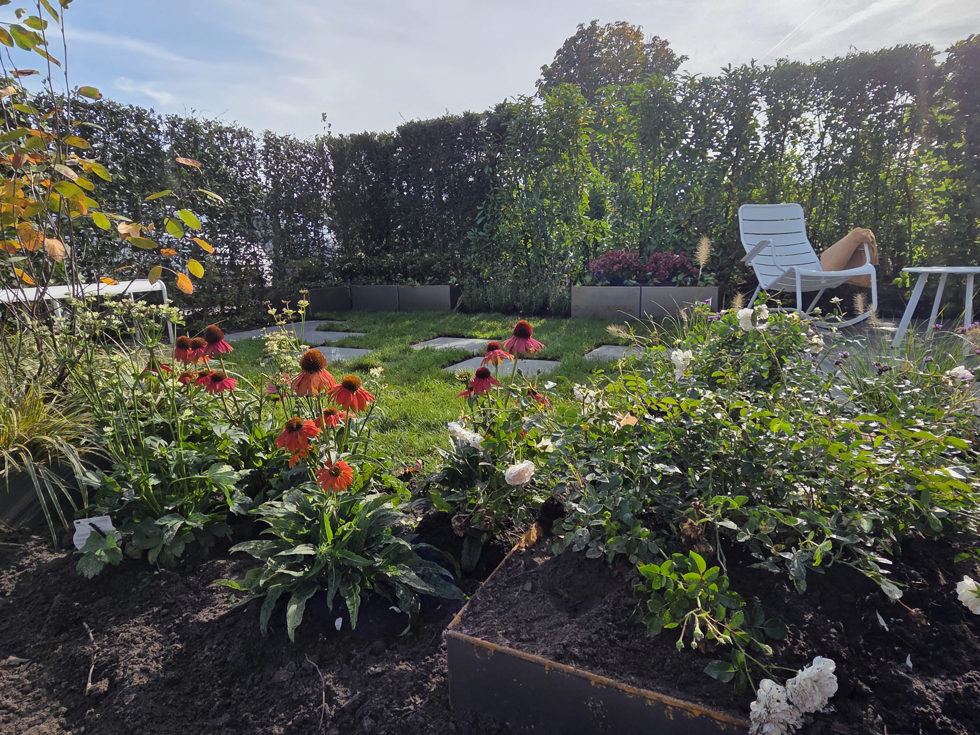 Garten mit bunter Bepflanzung, Gras, Trittsteinen und einem Sitzbereich als Anwendung des Preverde-Systems